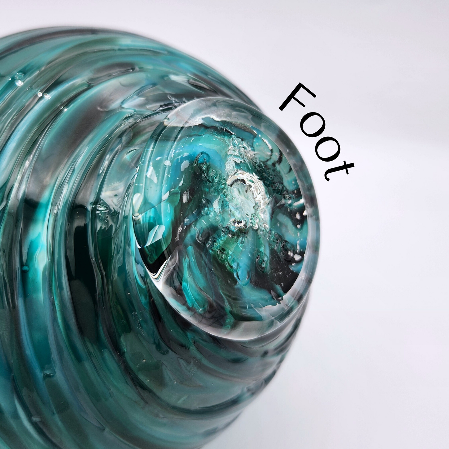 close up of a flat glass disc (we call it a foot) attached to the bottom of blown glass float. Not removable.